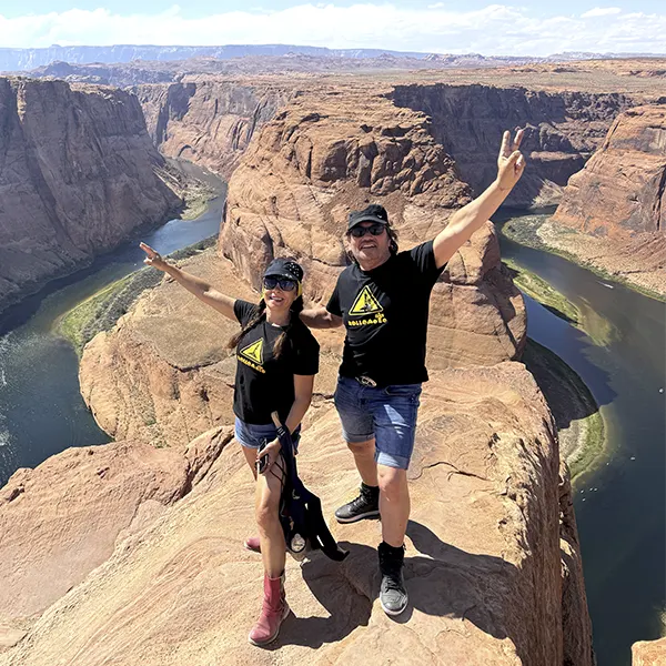 Pareja de viajeros en el Gran Cañón de Colorado disfrutando del paisaje y posando con la señal de victoria
